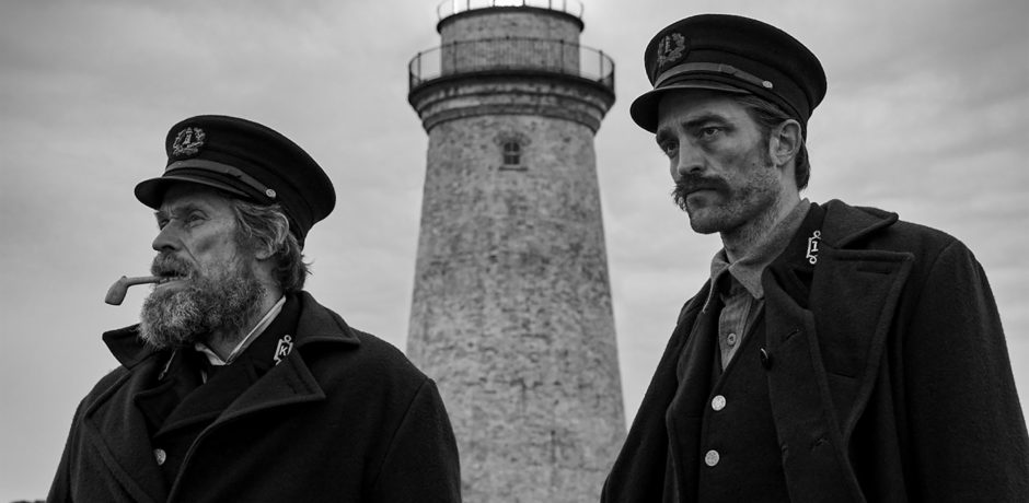 2 men stand in front of a lighthouse